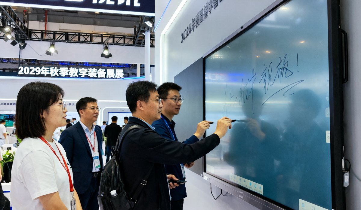2025年秋季教育装备展上DS视讯的展位，参观者正在体验智慧会议平板的触控书写功能，展位上方悬挂着品牌横幅